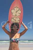 Female surfer carrying surfboard at beach