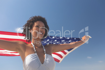 Woman holding american flag at beach