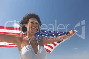 Woman holding american flag at beach
