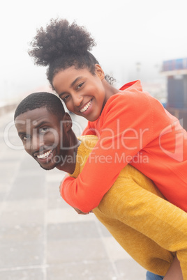 Man carrying woman piggyback at pavement