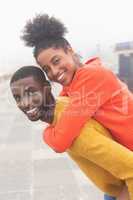 Man carrying woman piggyback at pavement