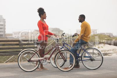 Couple interacting with each other while holding bicycle