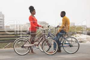 Couple interacting with each other while holding bicycle