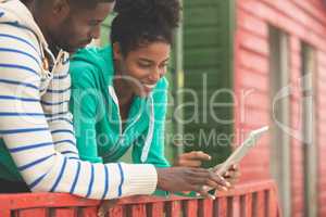 Couple using digital tablet while standing at beach hut
