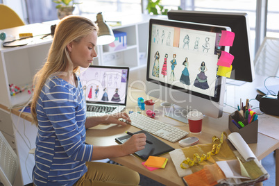 Female fashion designer using graphic tablet while working at desk