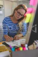 Female fashion designer drawing sketches at desk