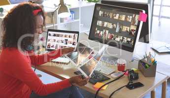 Female graphic designer looking photographs at desk