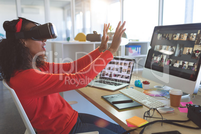 Female graphic designer using virtual reality headset at desk