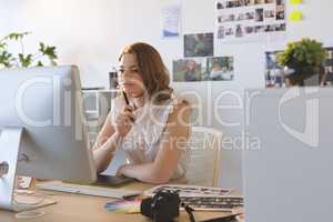 Female graphic designer working on graphics tablet and computer at desk