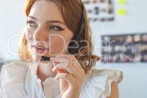 Female graphic designer talking on headphone in office