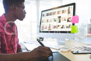 Graphic designer working on graphic tablet and computer at desk in office