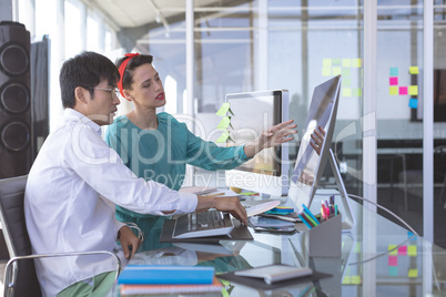 Business people discussing over computer at desk in office