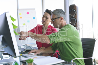 Business people discussing over computer at desk in office