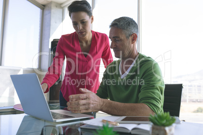 Attentive business people discussing over laptop at desk in office