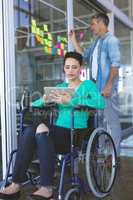 Disabled female executive using digital tablet while male executive writing on sticky notes