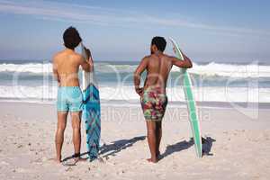 Young men with surfboard standing at beach in the sunshine