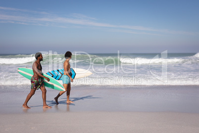 Young men with surfboard walking at beach in the sunshine