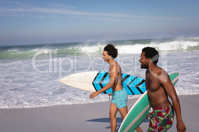 Young men with surfboard walking at beach in the sunshine