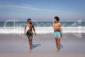 Young men with surfboard walking at beach in the sunshine