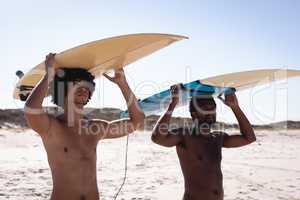 Young men carrying their surfboards on their head at the beach