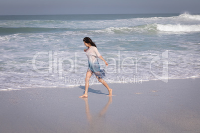 Young beautiful woman walking at beach in the sunshine