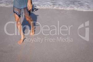 Young woman walking at beach in the sunshine