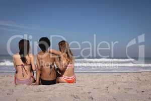 Young women sitting at beach in the sunshine