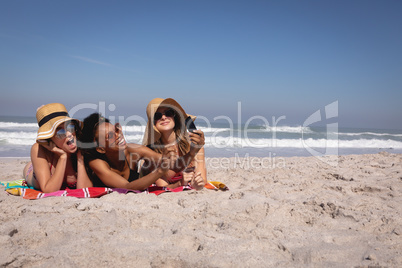 Happy beautiful young women with hat and sunglasses taking selfie on the beach