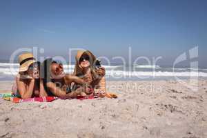 Happy beautiful young women with hat and sunglasses taking selfie on the beach