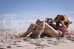 Beautiful young women lying and drinking beer at beach in the sunshine