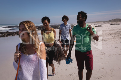 Group of friends walking on beach in the sunshine