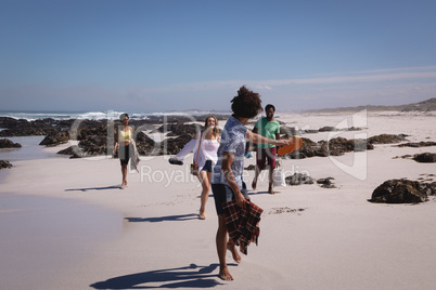 Group of friends walking on beach in the sunshine