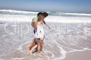 Happy group of friends walking on beach with arms around the waist