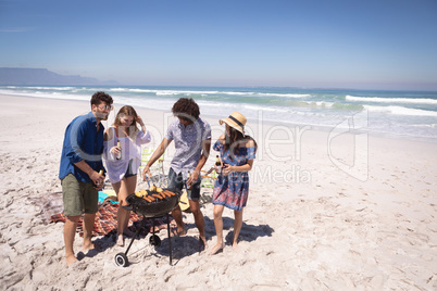 Group of friends surrounding of barbecue at beach