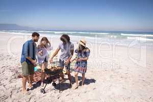 Group of friends surrounding of barbecue at beach
