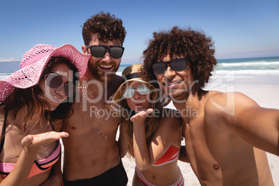 Happy group of friends looking at camera on beach in the sunshine