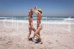 Beautiful young women with hat and sunglasses dancing at beach in the sunshine