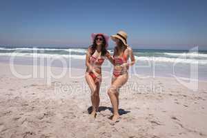 Beautiful young women with hat and sunglasses dancing at beach in the sunshine
