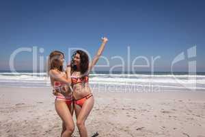 Beautiful young women in bikini dancing at beach in the sunshine