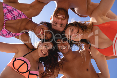 Low angle view of group of friends with arm around looking at camera at beach