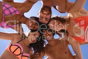 Low angle view of group of friends with arm around looking at camera at beach