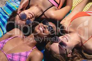 Happy beautiful young women with sunglasses lying on beach in the sunshine