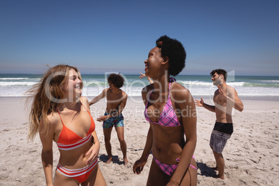 Happy group of friends dancing together on beach in the sunshine