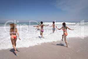Group of friends running in ocean waves