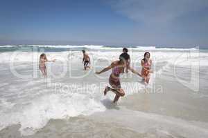 Happy group of friends playing on ocean waves