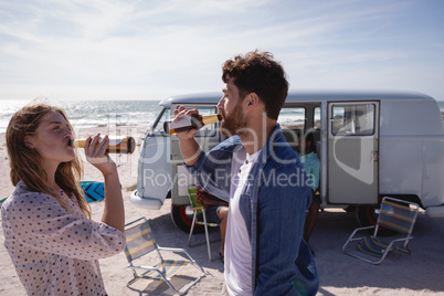 Friends drinking beer on beach in the sunshine