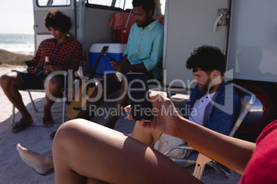 Group of friends using mobile phone near a camper van