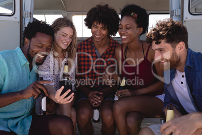 Group of friends laughing together while they drinking beer bottle