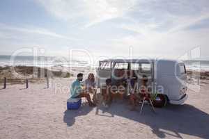 Group of friends enjoying at beach near their camper van