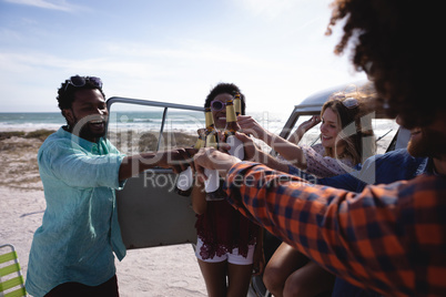 Group of friends toasting beer bottles at beach